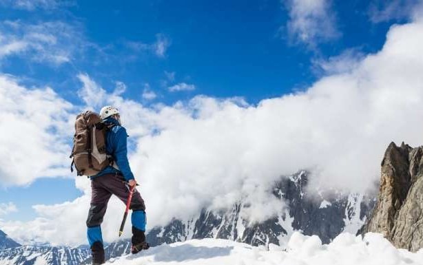 A trekker standing in front of Diran Peak (7277M), a stunning snow-capped peak in the Karakoram Range, offering one of the most scenic mountaineering trips in Pakistan.